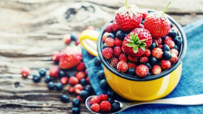 Red berries in a bowl on a wooden surface