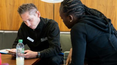 A student facing their tutor sitting opposite reading through a training manual