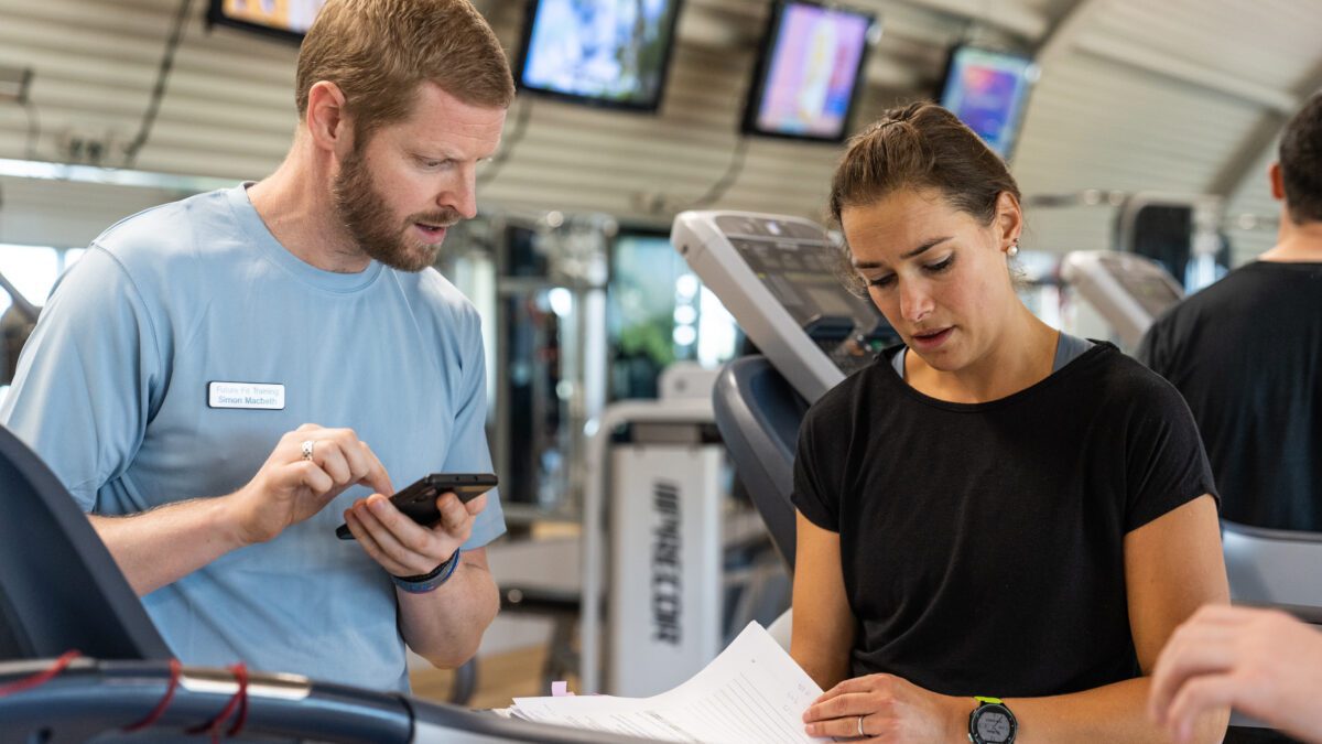 Personal training course tutor talking student through an exercise