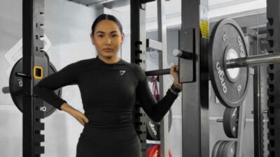 A woman standing in a squat rack holding a barbell