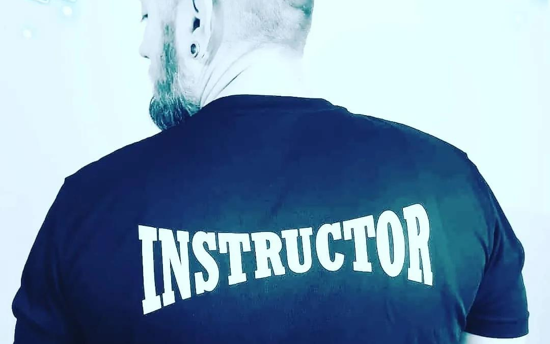 A man with his back to the camera with the word Instructor on the back