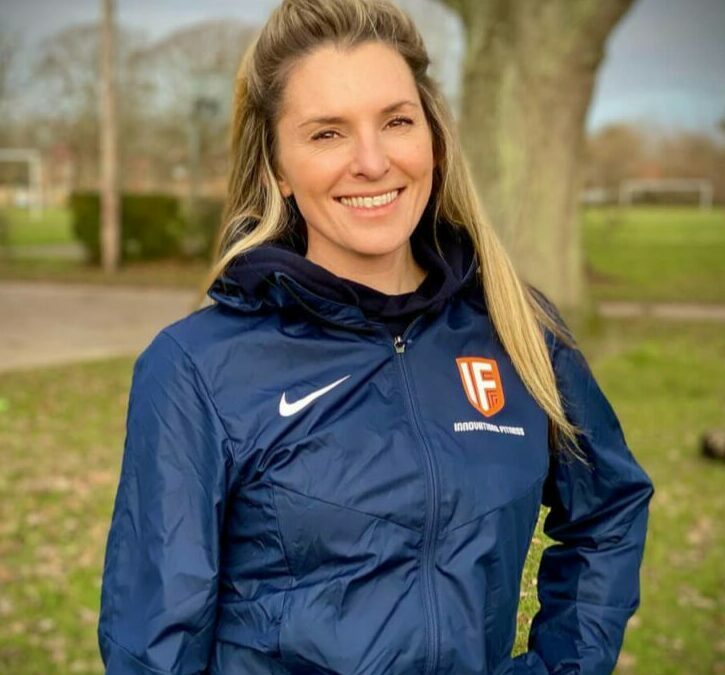 Young woman with blonde hair wearing a sports jacket smiling at the camera