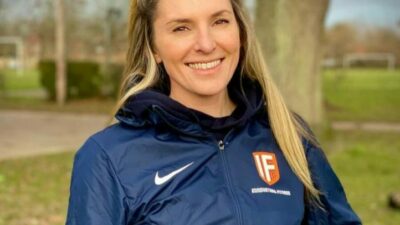 Young woman with blonde hair wearing a sports jacket smiling at the camera